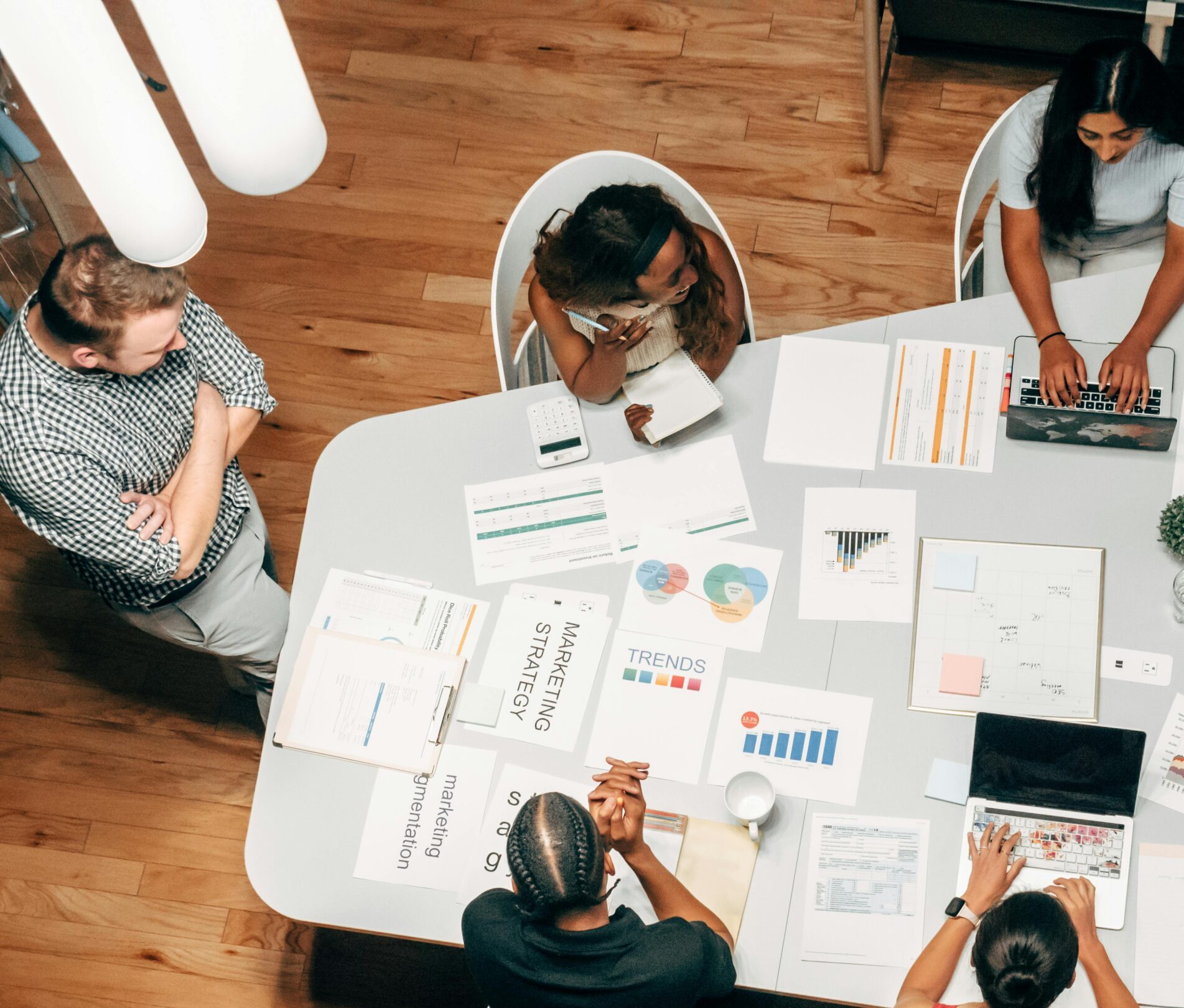 A diverse group working on marketing strategies with charts and laptops in an office setting.