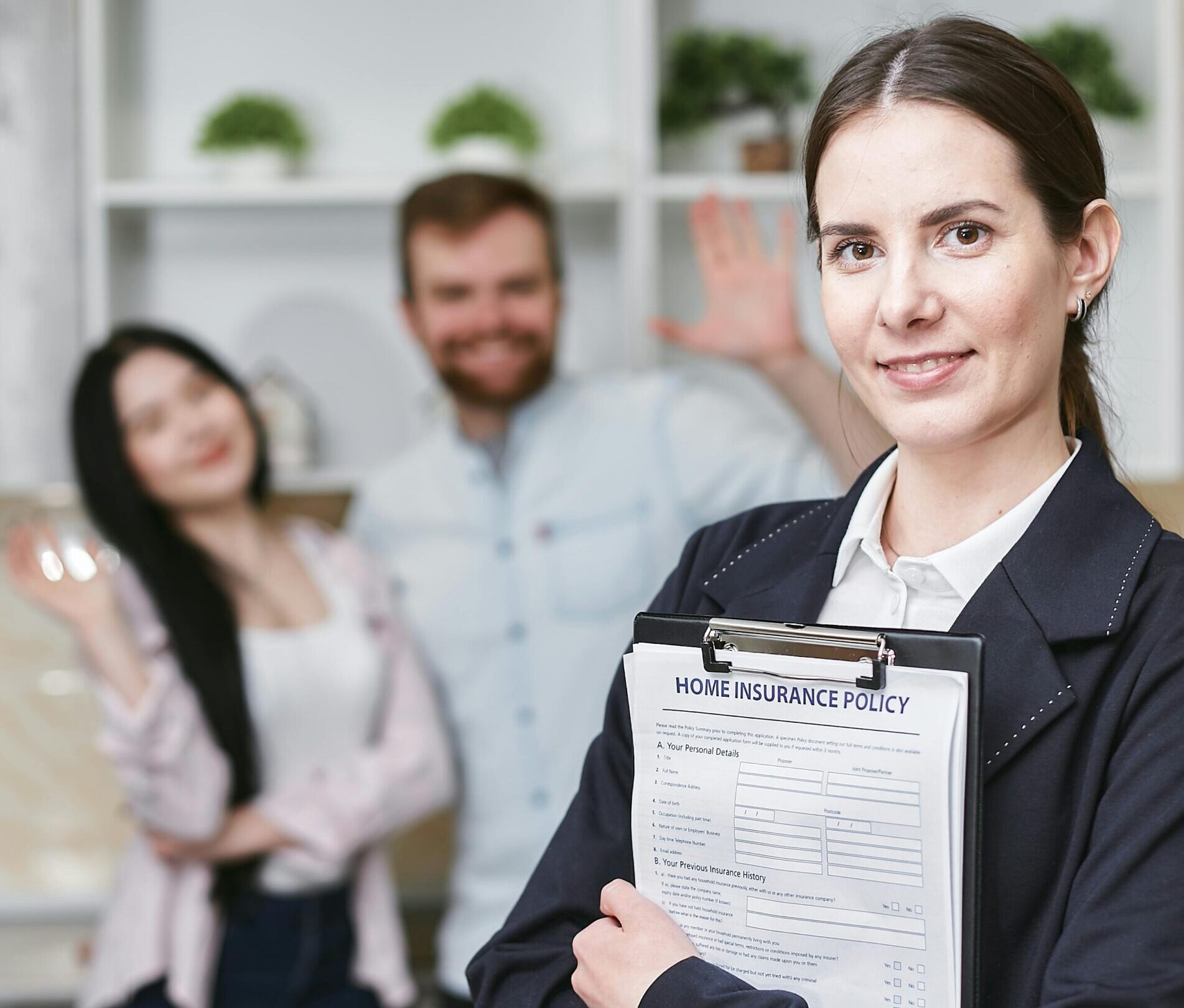 A smiling businesswoman holding a home insurance policy with clients in the background.