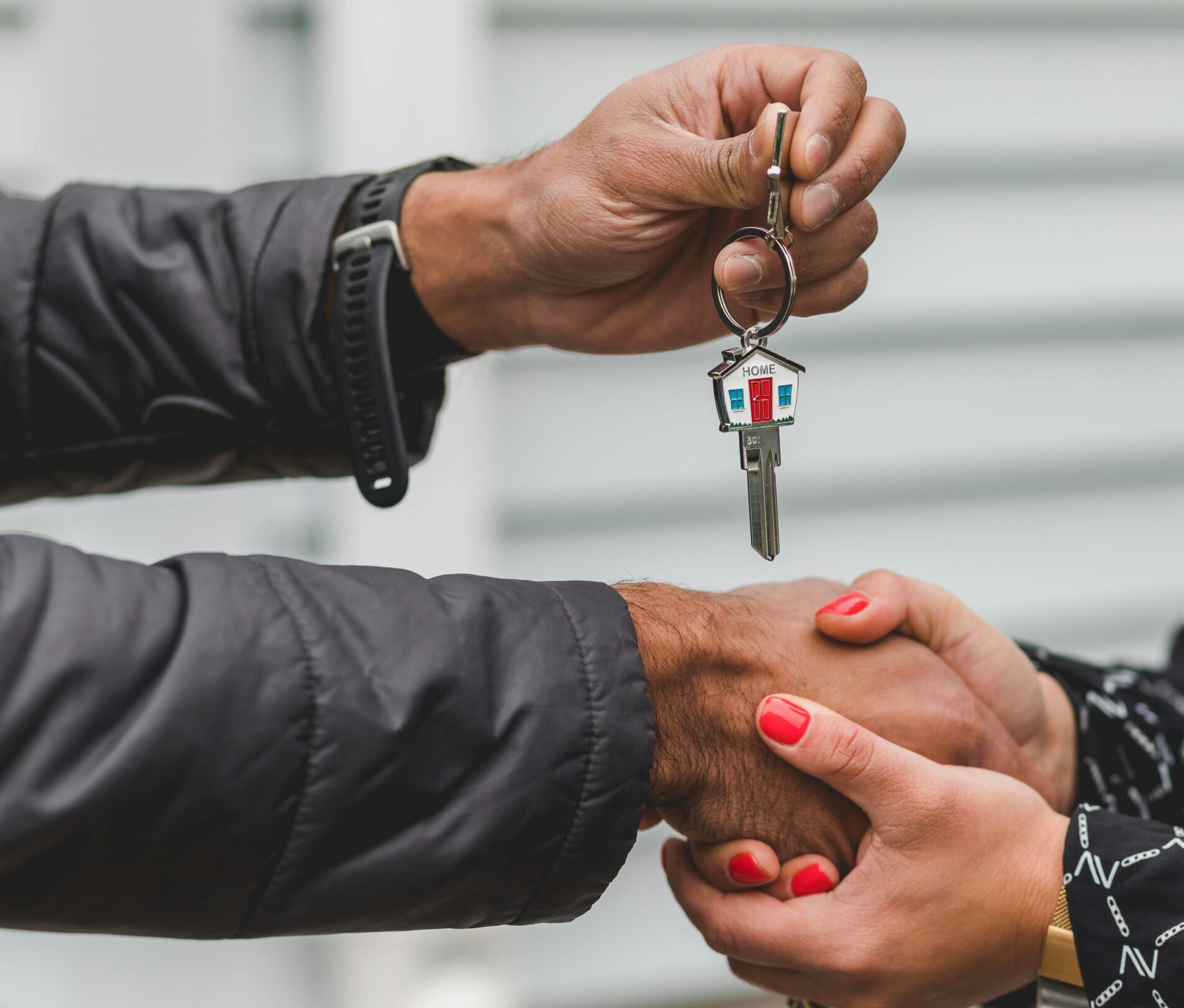 Close-up of a realtor handing over a house key to a new homeowner, symbolizing ownership and investment.